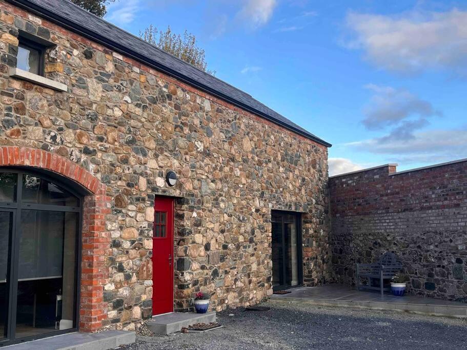un edificio de ladrillo con una puerta roja a un lado en The Stone Barn, en Magheralin