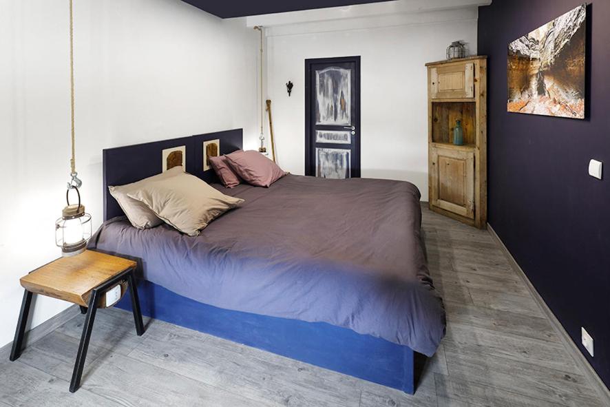 a bedroom with a large bed and a chair at La Belle Rivière in Bolozon