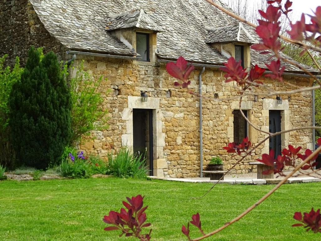een oud stenen huis met een grasveld bij Gîte La Laiterie - La Planhe in Bozouls