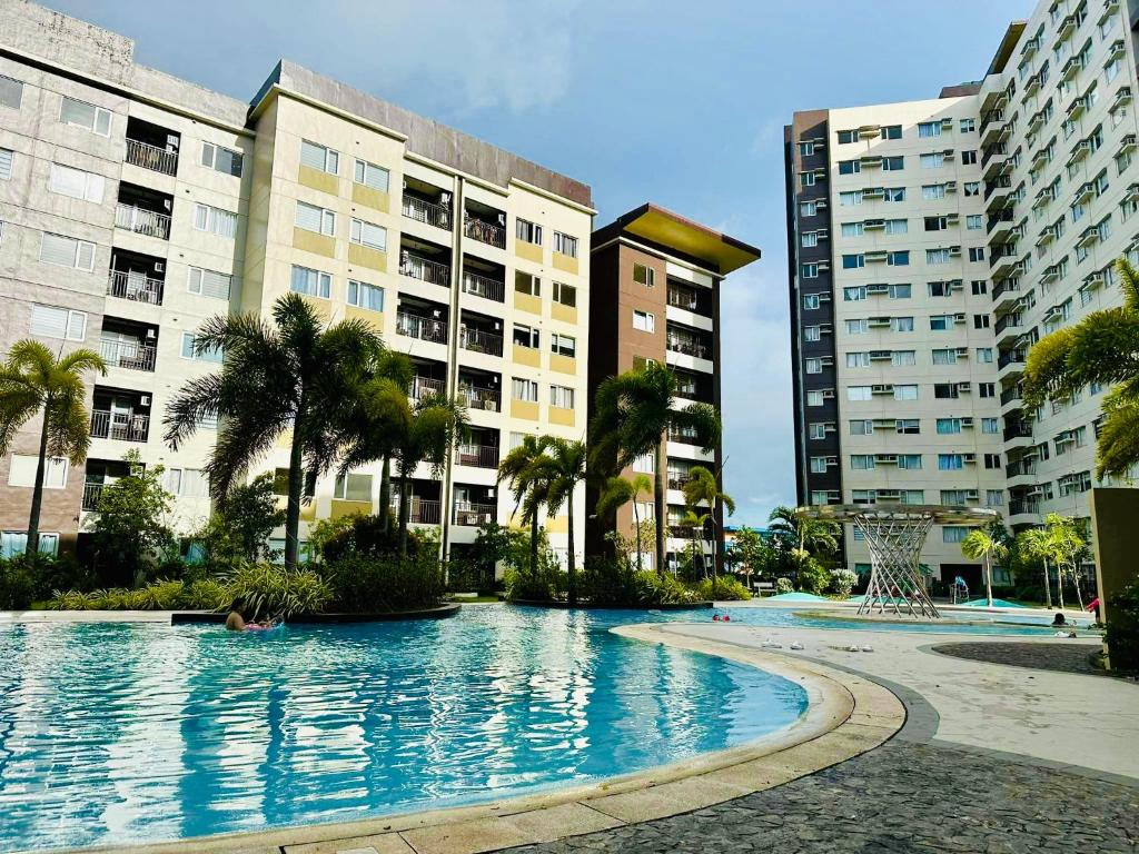 a large swimming pool with palm trees and buildings at AVIDA ATRIA TOWER 3 Unit 3-320 in Iloilo City