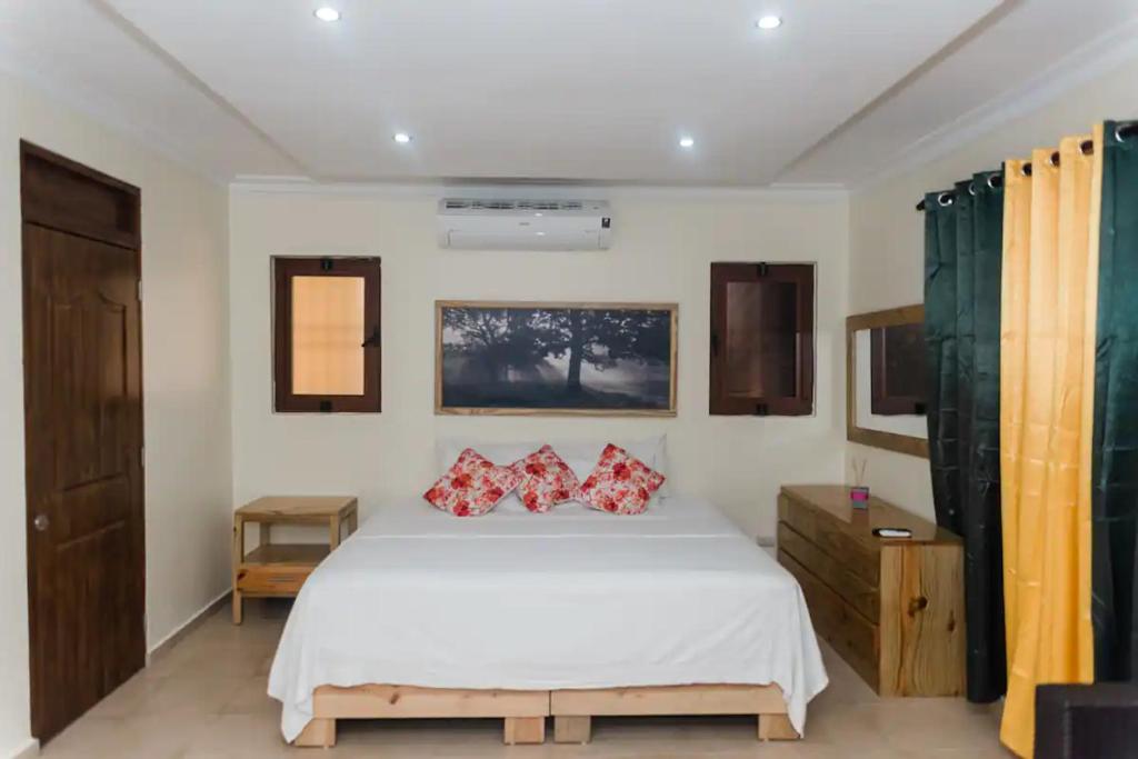 1 dormitorio con cama blanca y almohadas rojas en Verde Bonavita, en Santiago de los Caballeros