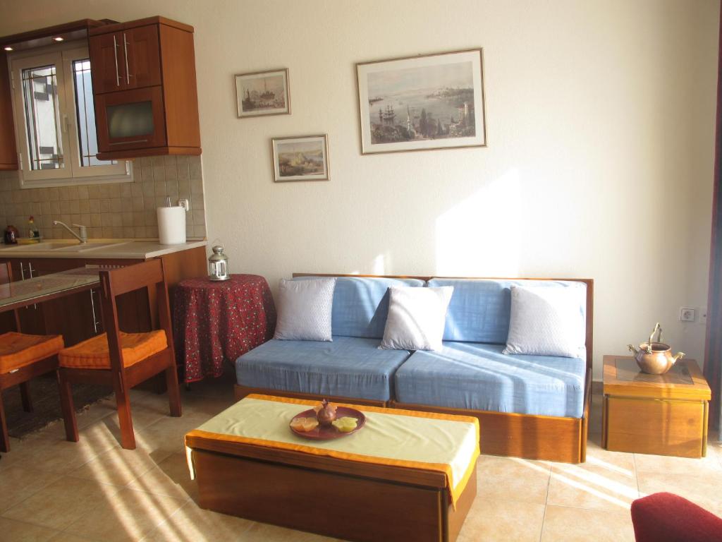 een woonkamer met een blauwe bank en een keuken bij One Home ~ Fits All in Mouzákion