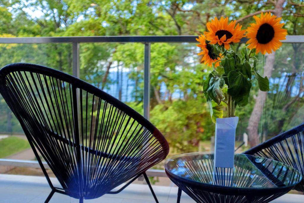 twee stoelen en een glazen tafel met een vaas van bloemen bij Lucky40 - Apartament z widokiem na morze, SPA gratis, Dwie Sosny in Ustronie Morskie