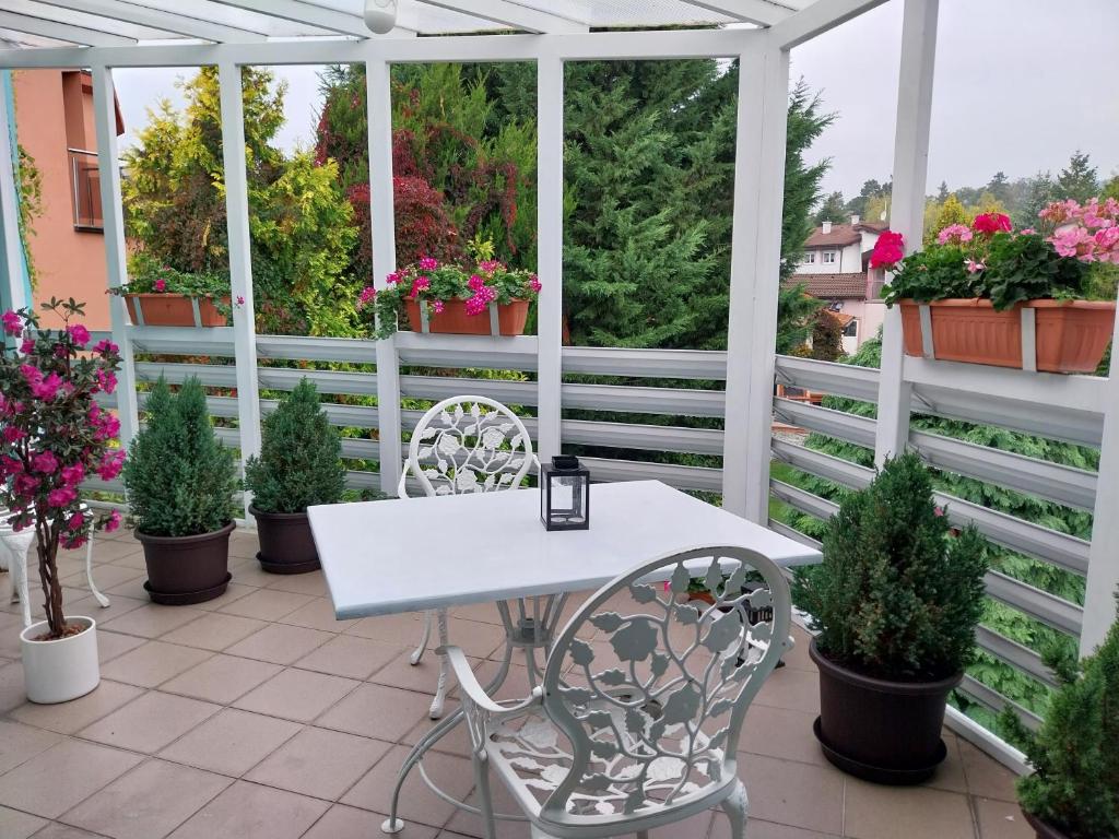 a white table and chairs on a patio with potted plants at Cozy rooms in wine town - Modra in Modra