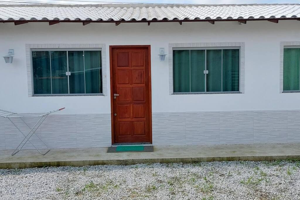 Una porta rossa sul lato di una casa bianca di Casa tranquila 2 Q, bem localizada, ar opcional wifi grátis. ad Araruama