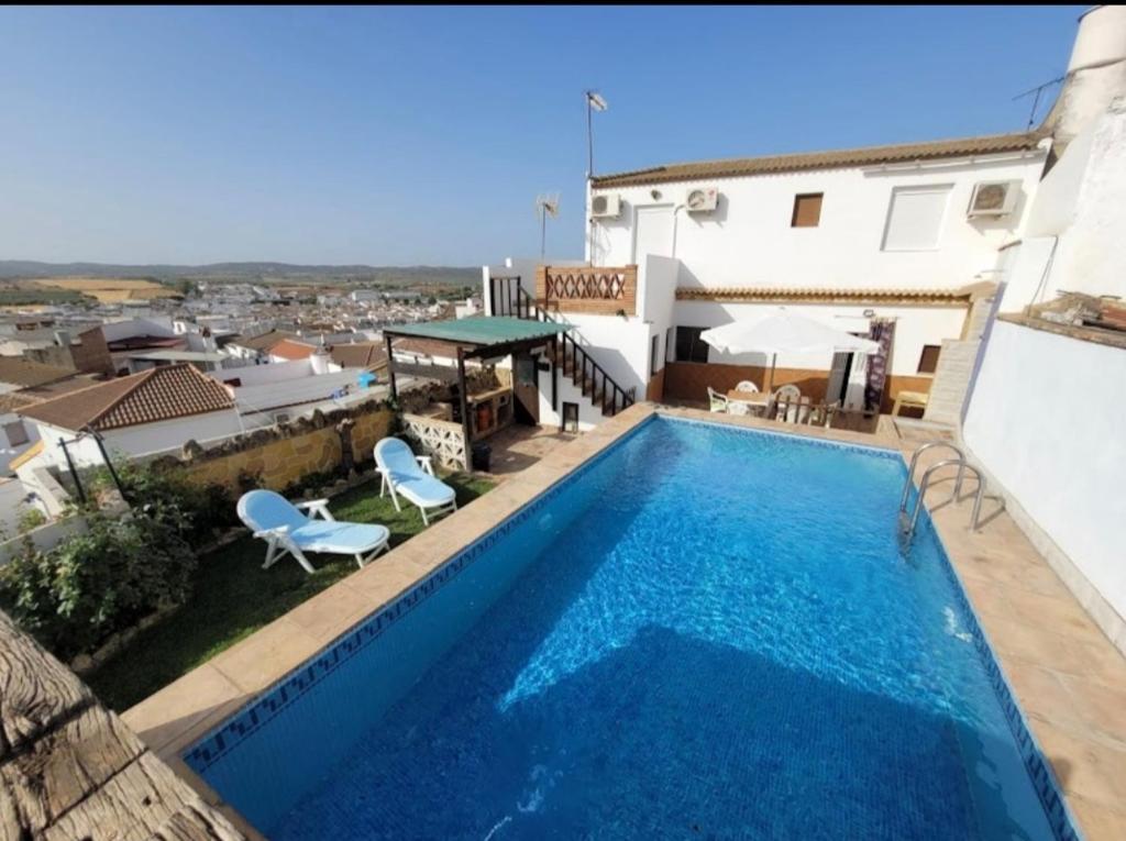 uma piscina com duas cadeiras e uma casa em Casa rural el castillo em La Puebla de los Infantes