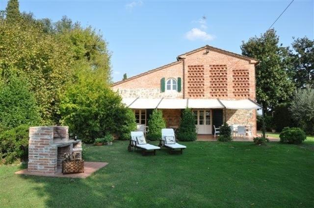 uma casa de tijolos com duas cadeiras e uma lareira em Villa Fontine by PosarelliVillas em Orentano