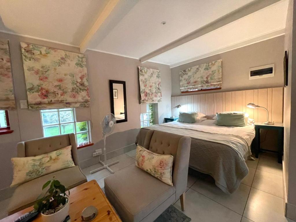 ein Schlafzimmer mit einem Bett, einem Sofa und Fenstern in der Unterkunft EdenNook in George