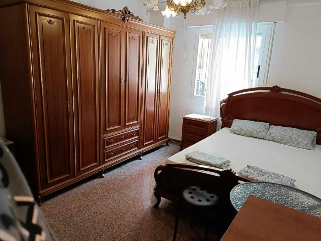 1 dormitorio con 1 cama y armarios de madera en Habitacion, en Alicante