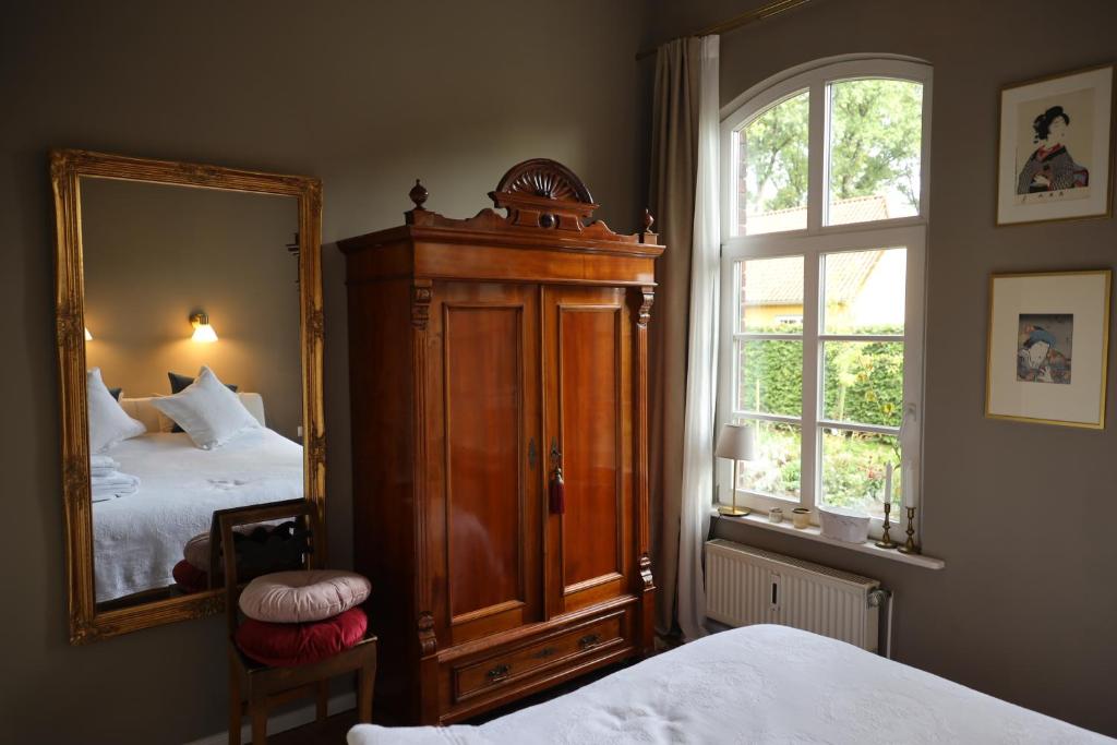 1 dormitorio con espejo grande y cama en Altes Schulhaus in der Lüneburger Heide, en Lachendorf