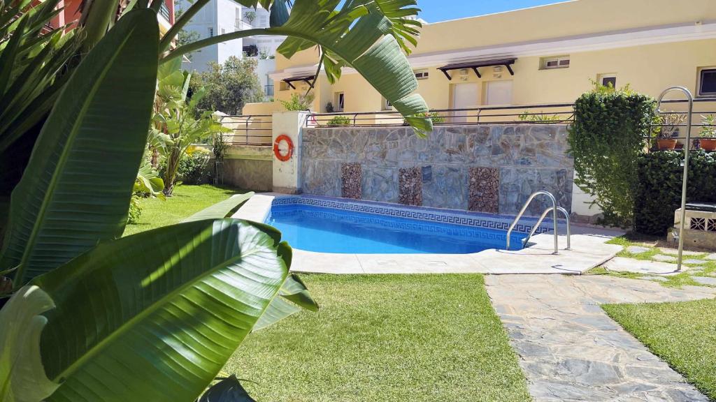 a swimming pool in a yard next to a house at Nuevo con Piscina y Parking en la Playa in Torre de Benagalbón