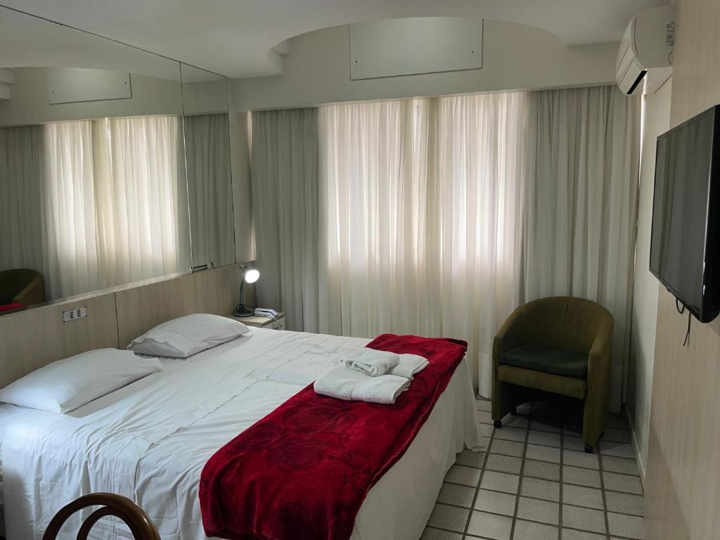 a hotel room with a large bed and a chair at Loft com vista da praia da Costa 612 in Vila Velha
