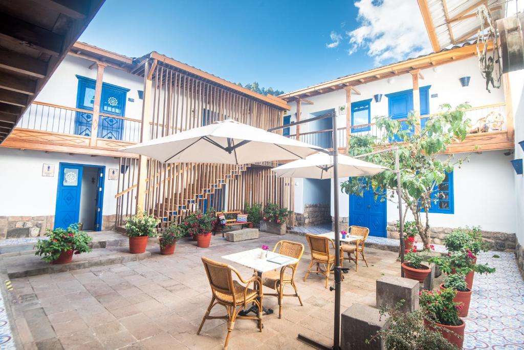 un patio con mesas, sillas y una sombrilla en Quinta San Blas by Ananay Hotels en Cuzco