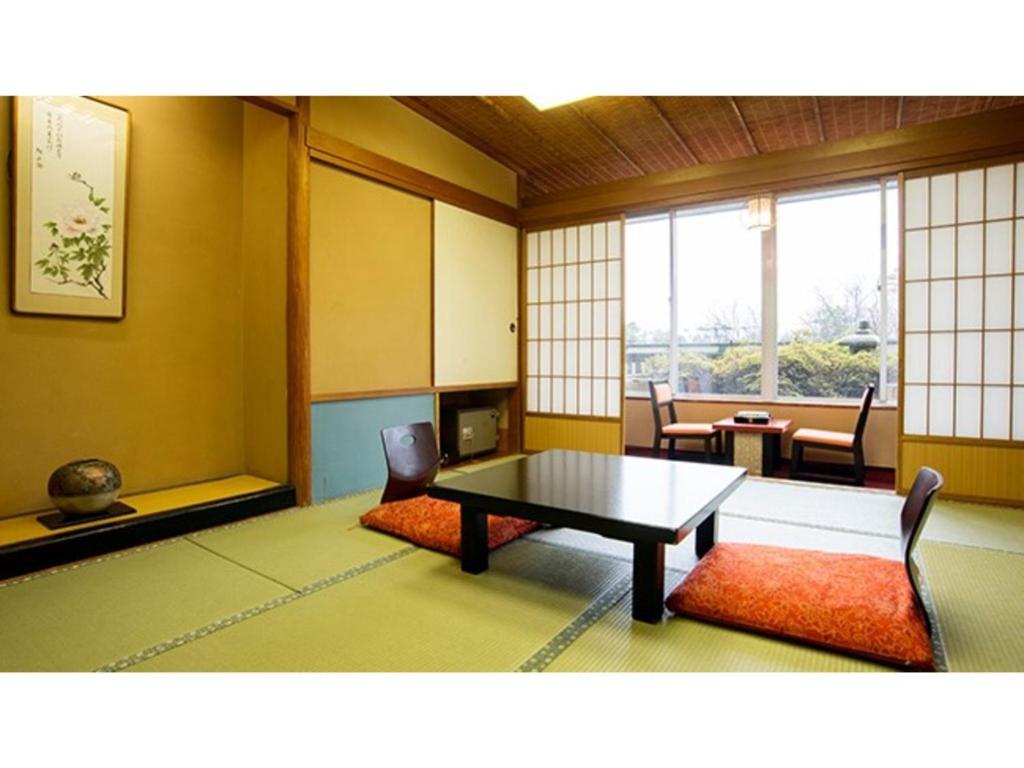 Zimmer mit einem Tisch, Stühlen und Fenstern in der Unterkunft Yamashiro Onsen Yuzankaku - Vacation STAY 86430v in Kaga