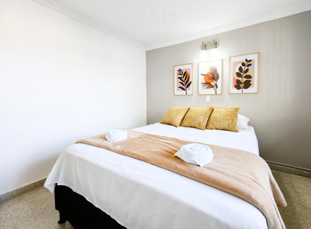 a bedroom with a large bed with white sheets and gold pillows at Aparta Hotel Downtown Guatapé in Guatapé