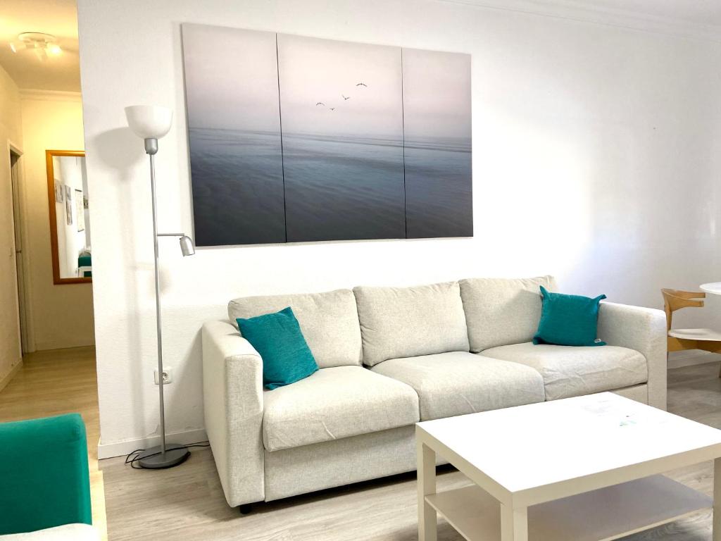 ein Wohnzimmer mit einem weißen Sofa und blauen Kissen in der Unterkunft Cozy and modern apartment in Maspalomas in San Fernando