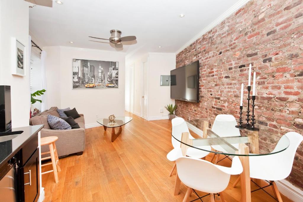 - un salon avec un mur en briques et une table en verre dans l'établissement Three Bedroom West Village Townhouse, à New York