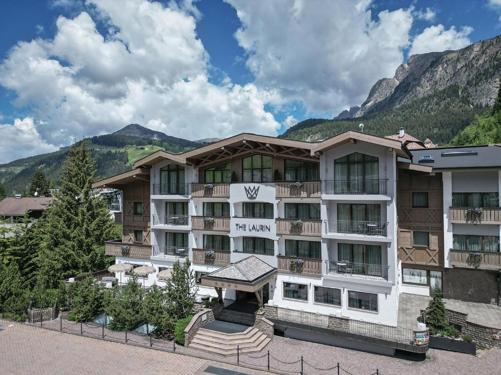 a large hotel with mountains in the background at The Laurin Small & Charming in Selva di Val Gardena