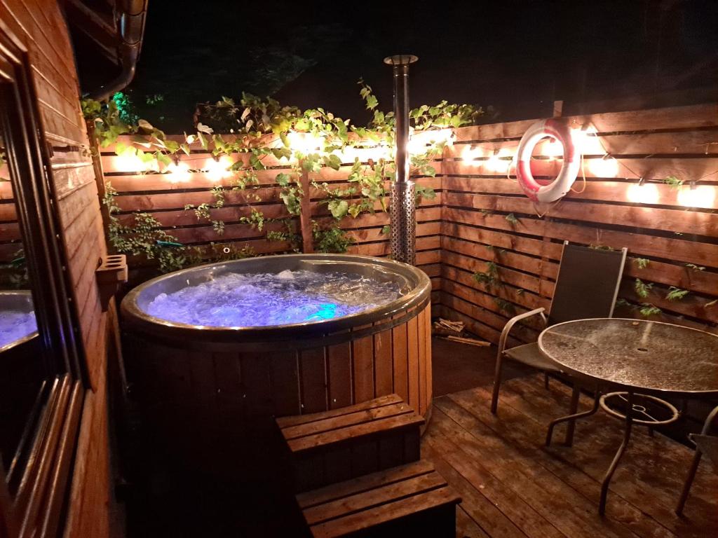 eine Whirlpool-Badewanne auf einer Terrasse mit einem Tisch in der Unterkunft Domek nad jeziorem in Gowidlino