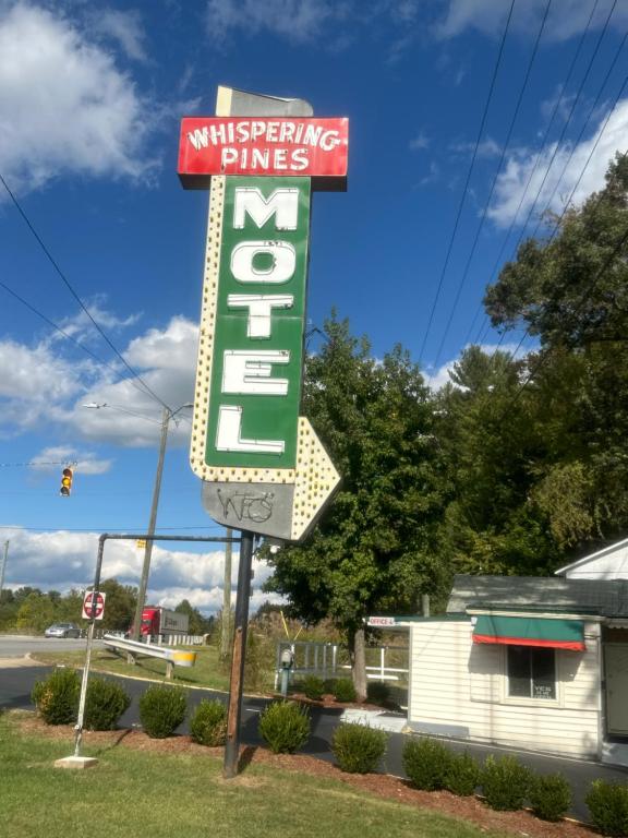 un cartel para un motel de pinos frente a un edificio en Whispering Pines Motel, en Asheville