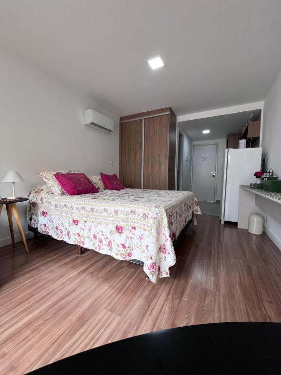 - une chambre dotée d'un lit avec un couvre-lit floral et d'un réfrigérateur dans l'établissement Studio GO Poços, à Poços de Caldas