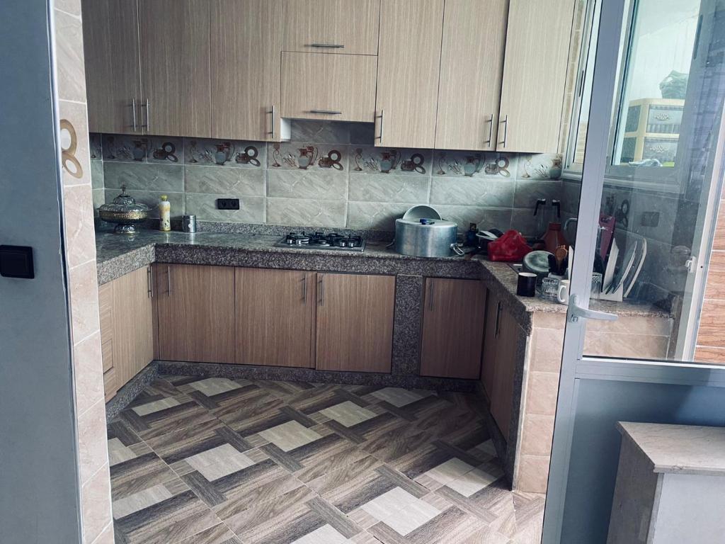 cocina con armarios de madera y suelo de baldosa en Appartement à louer 80 m² à Aourir - agadir en Aourir