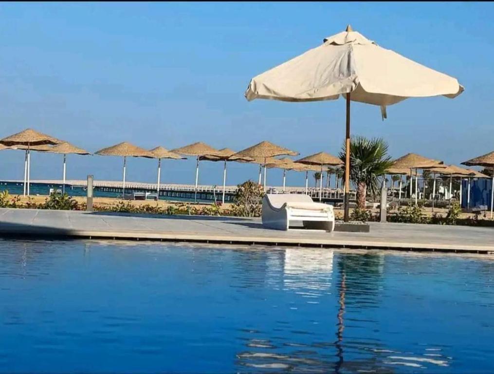 a pool with an umbrella and chairs and umbrellas at Scandic Resort One Bedroom Apartment in Hurghada