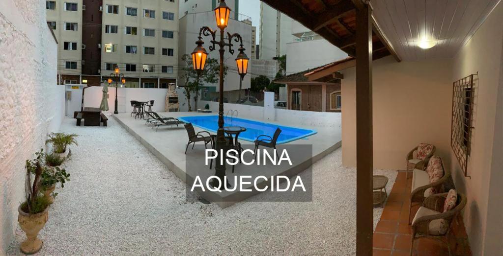 um pátio com uma mesa e cadeiras e uma piscina em Hotel Suiça Faber em Balneário Camboriú