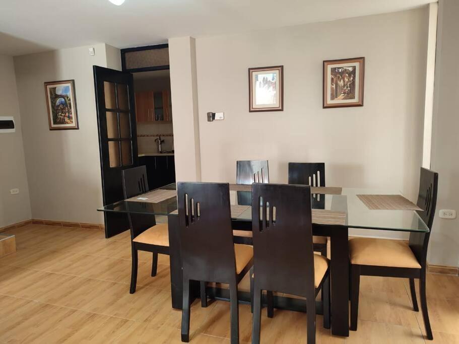 uma sala de jantar com uma mesa de vidro e cadeiras em Casa moderna con cochera en San Isidro Trujillo em Trujillo