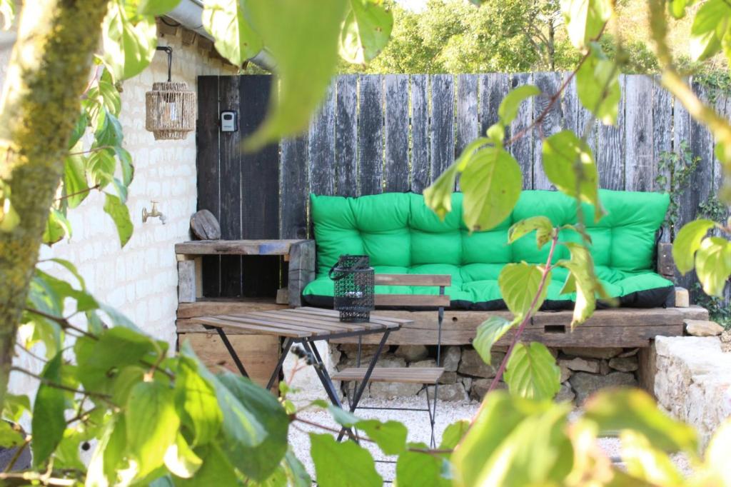 a green couch sitting on a table in a backyard at Studio à la campagne, proche Futuroscope in Beaumont