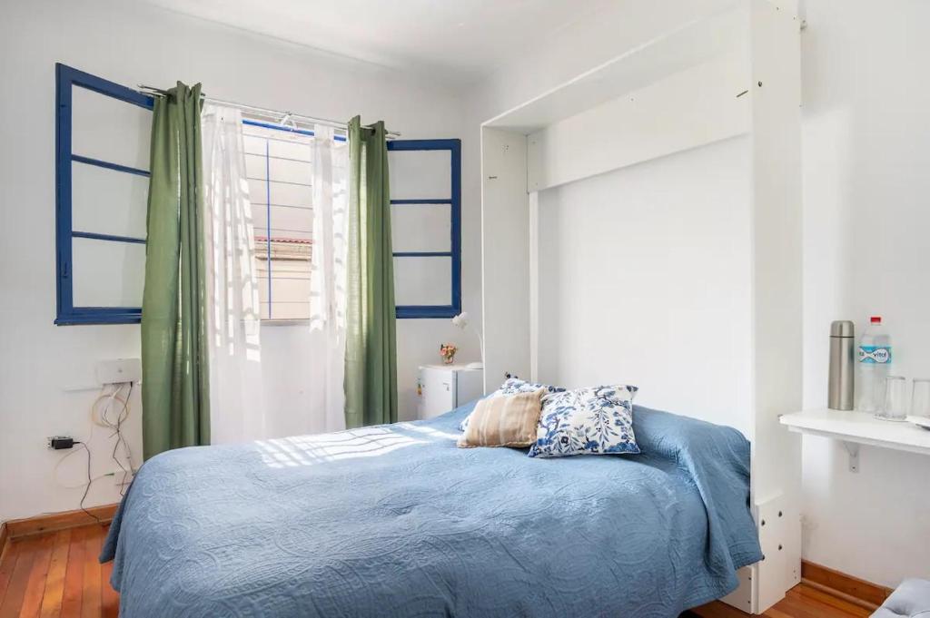 a bedroom with a bed with blue sheets and windows at Habitaciones privadas en Ñuñoa Estadio Nacional in Santiago