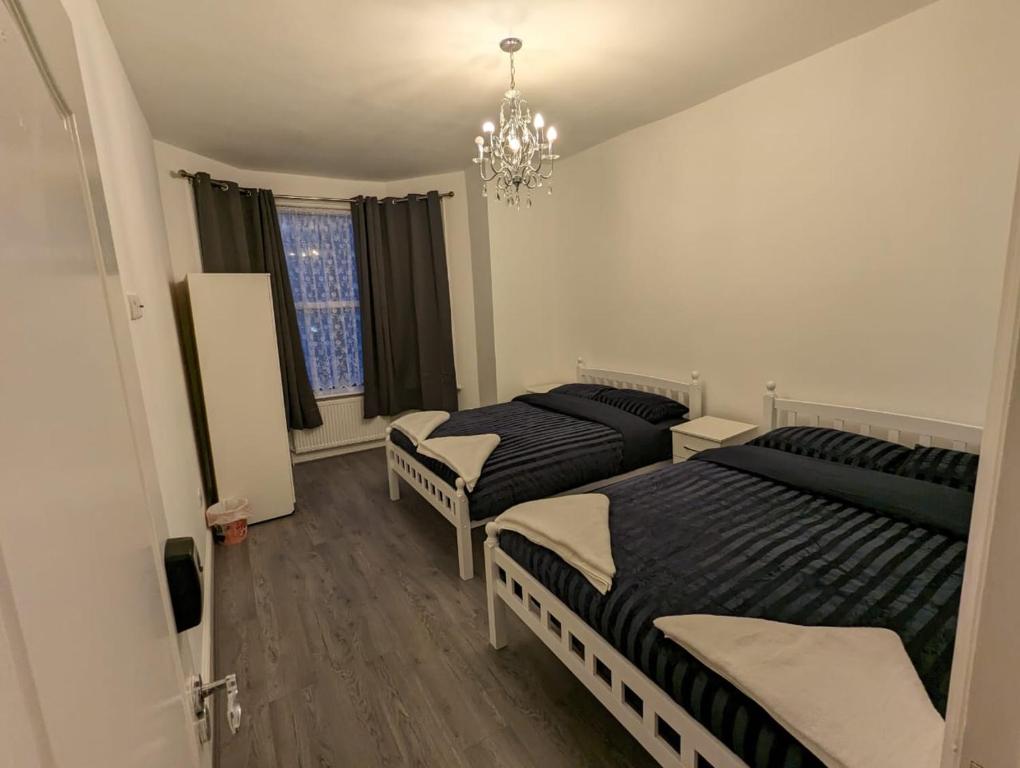 a bedroom with two beds and a chandelier at RAYAN'S LODGE STRATFORD in London