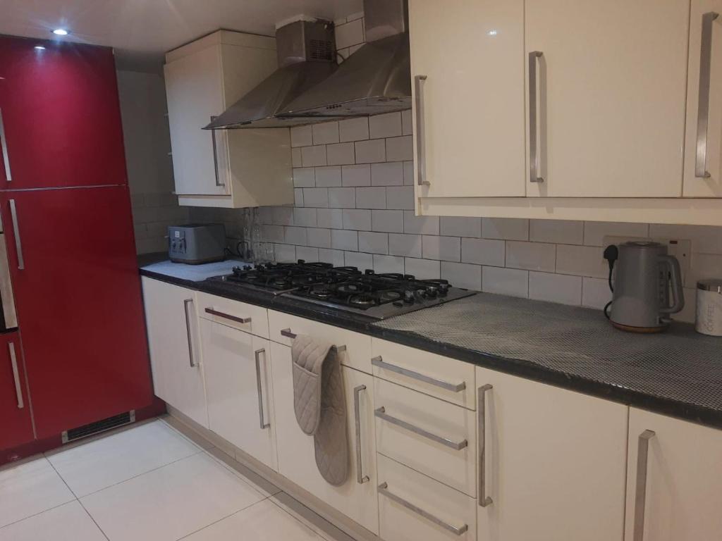 een keuken met witte kasten en een kookplaat oven bij Rayan's Lodge Stratford London by OYO in Londen