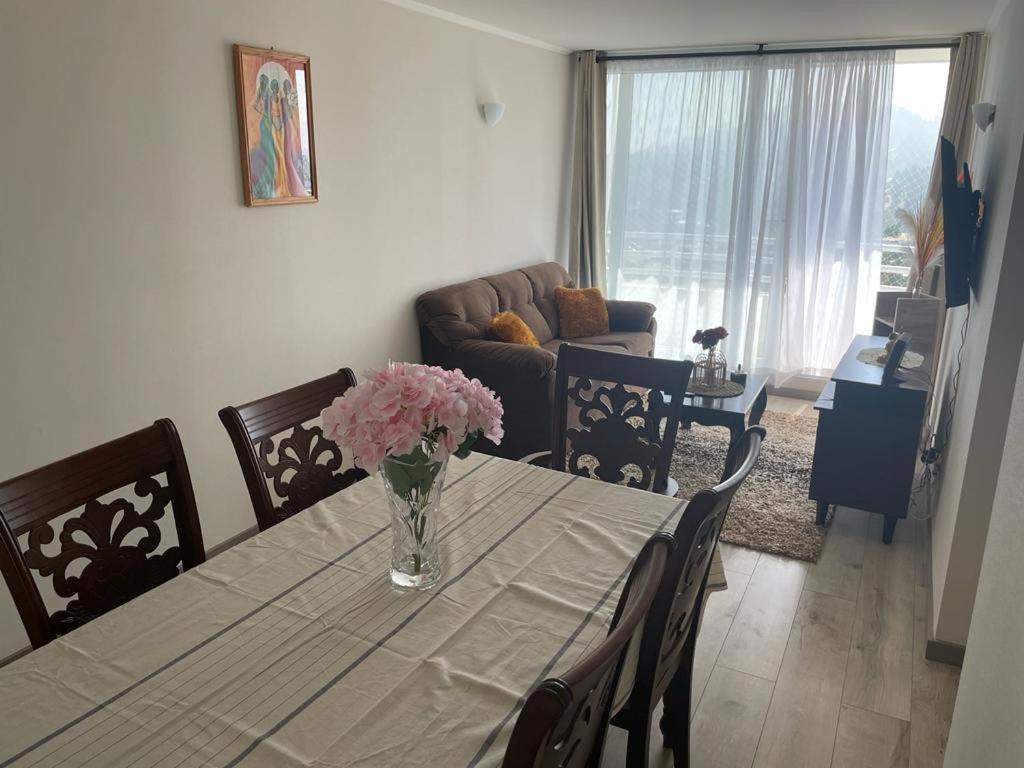 a dining room table with a vase of flowers on it at Departamento nuevo en reñaca alto 2 dormitorios in Viña del Mar