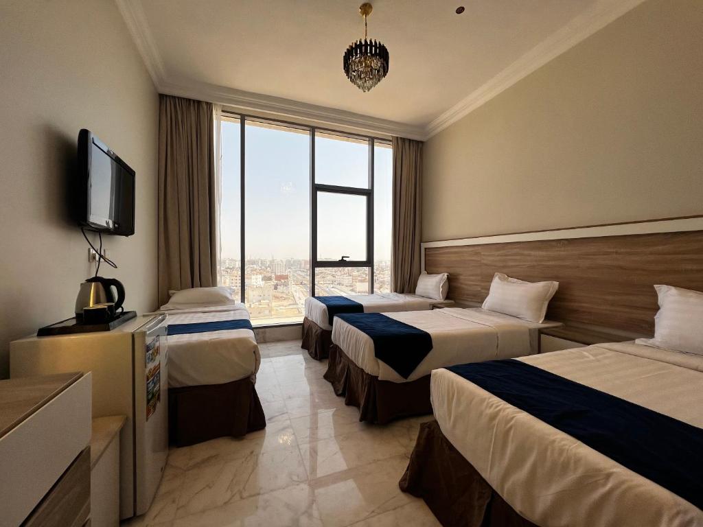 a hotel room with two beds and a television at Taiba Karim Hotel Madina in Al Madinah
