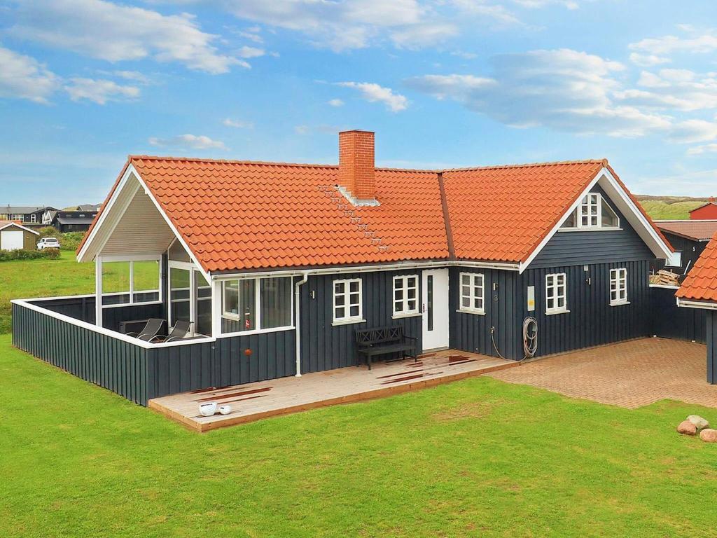 une grande maison noire avec un toit orange dans l'établissement Holiday home Løkken CXLVII, à Løkken