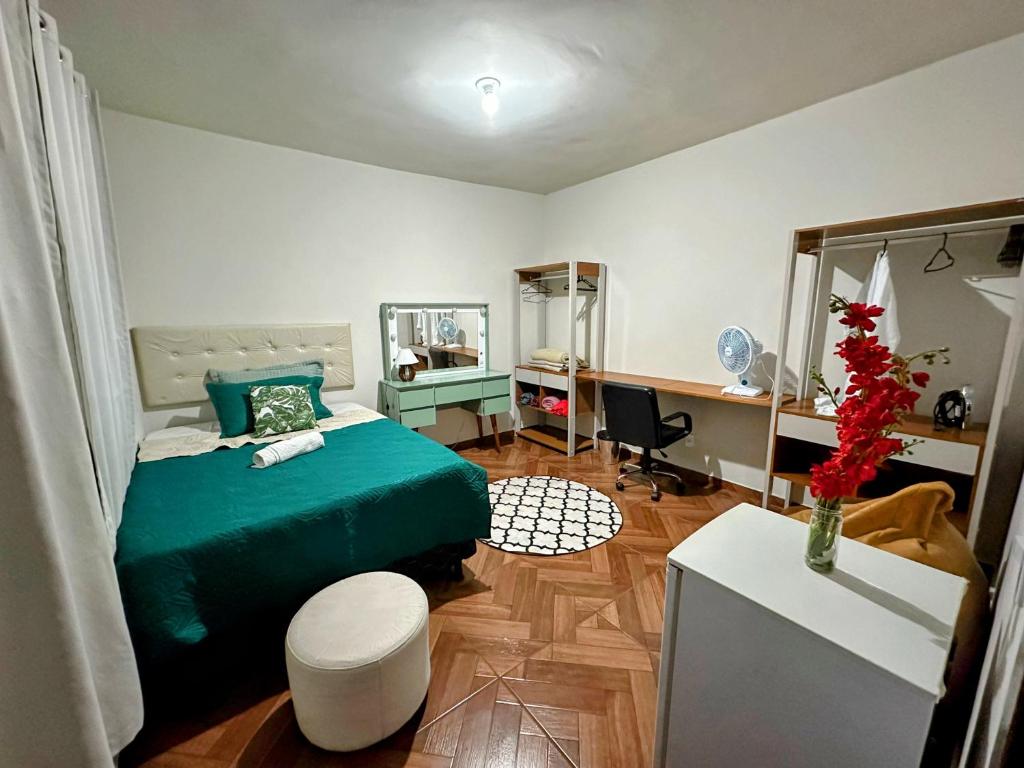 1 dormitorio con cama verde y escritorio en Espaço Nill, en Belo Horizonte