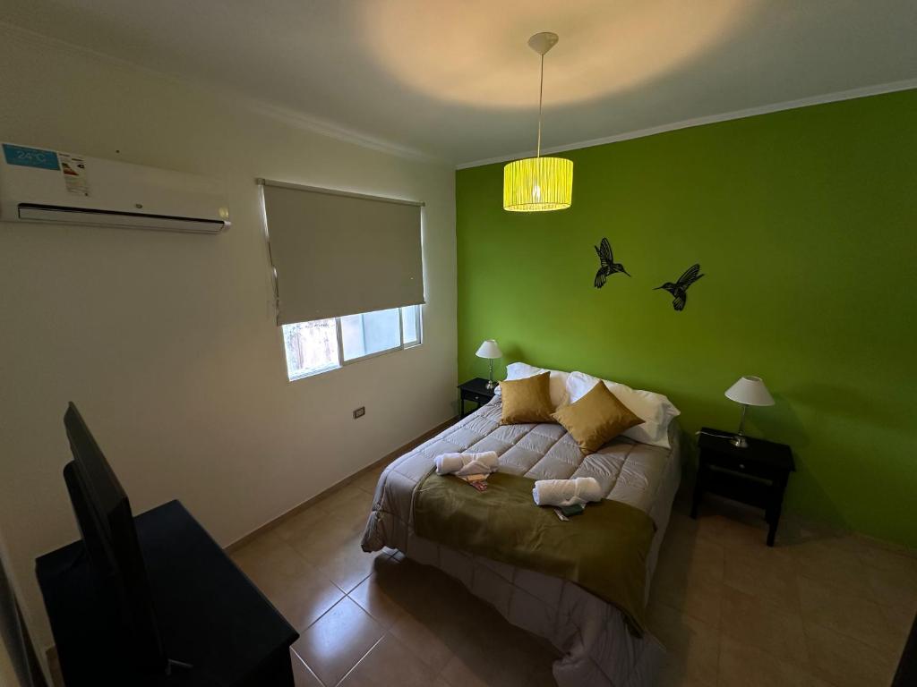 - une chambre verte avec un lit avec des oiseaux sur le mur dans l'établissement Departamentos Crisol, à San Fernando del Valle de Catamarca