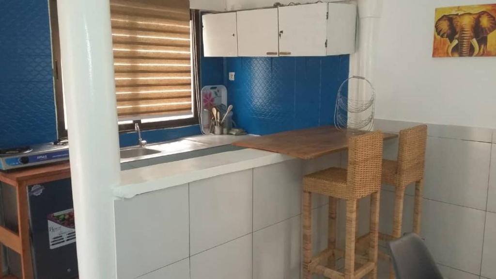 a kitchen with a sink and a counter with a stool at Studio Mpita in Pointe-Noire
