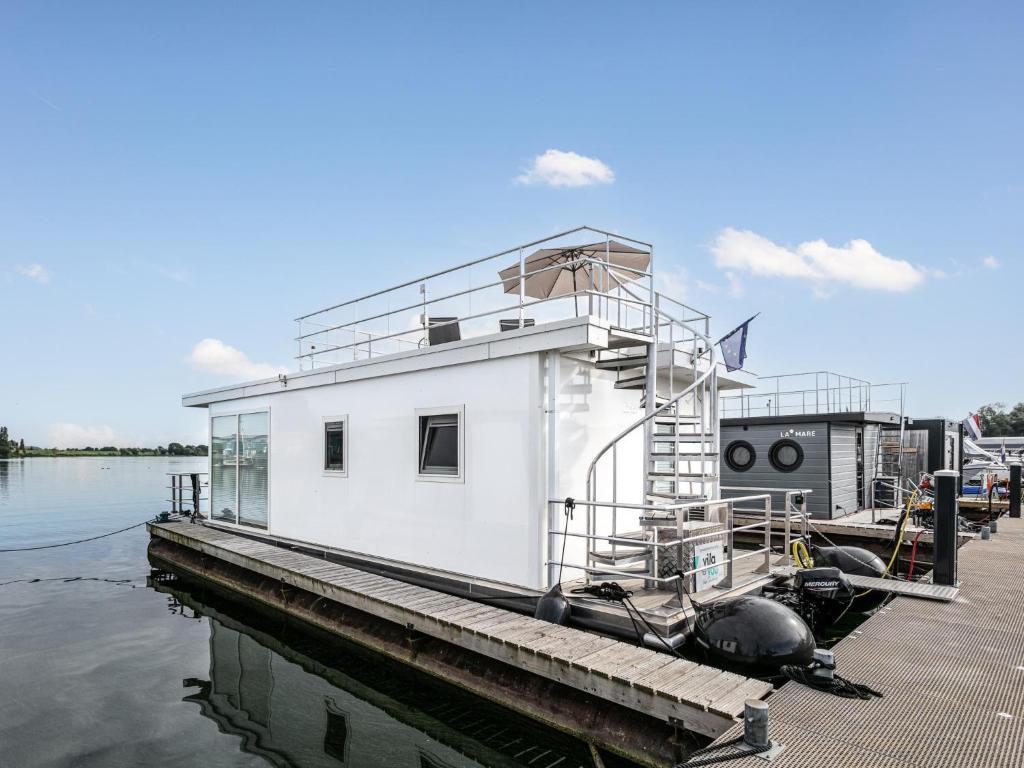 un barco blanco está atracado en un muelle en La Serafat, en Maasbommel