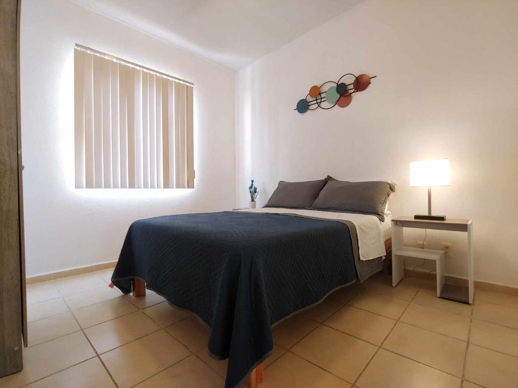 a bedroom with a bed with a blue blanket and a window at Renta. Departamento Acapulco alberca wifi aire acondicionado in Aguacatillo