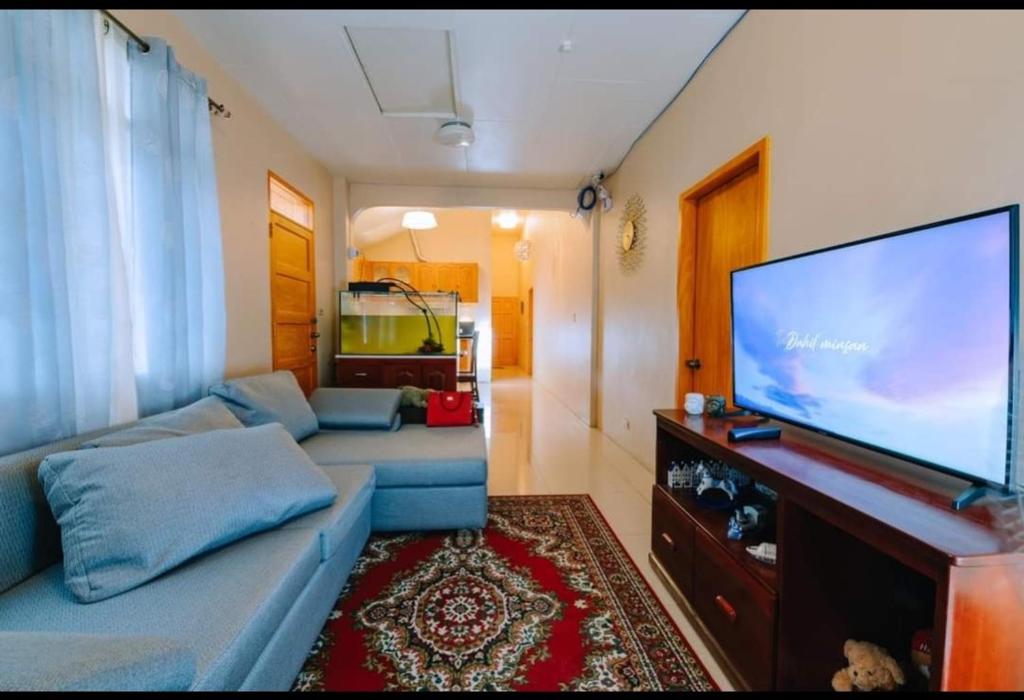 sala de estar con sofá azul y TV de pantalla plana en Malibu Homes, en Casisang