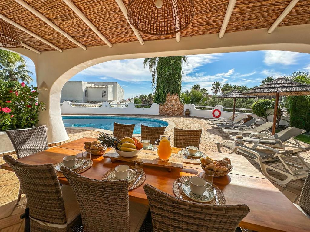 a dining room with a table and chairs and a pool at Luxury Villa Heated Pool, walk to São Rafael Beach, Albufeira in Albufeira