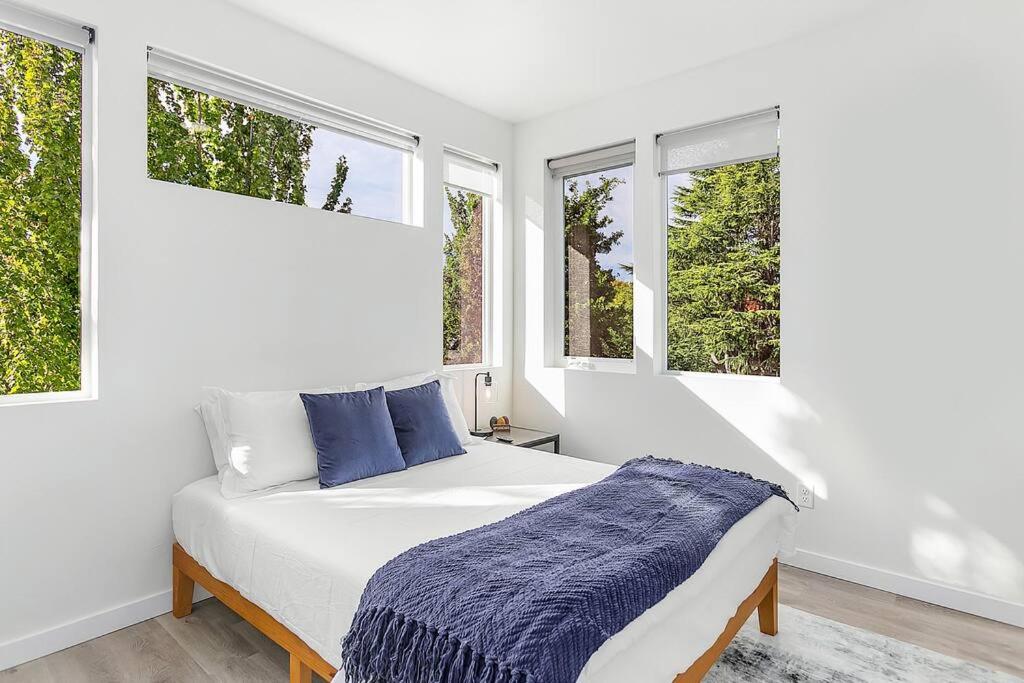 a white bedroom with a bed and two windows at Vhagar's Valyria's Vista in Seattle