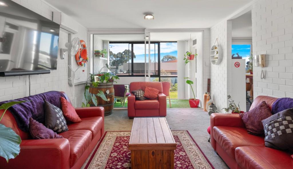 salon z 2 czerwonymi kanapami i stołem w obiekcie A Larger Slice of Fremantle 3bed apt. Wifi-Netflix w mieście Fremantle