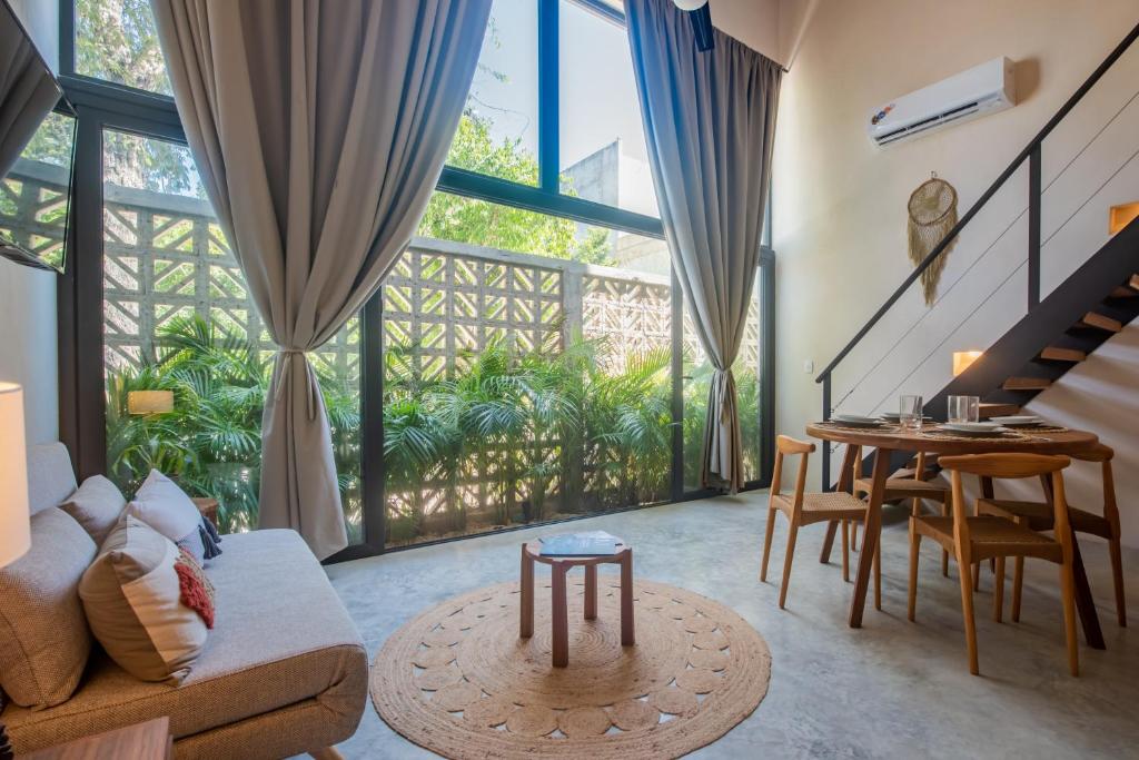 a living room with a couch and a table at Bright 2BR Loft with Rooftop Pool in Best Tulum Downtown Location in Tulum