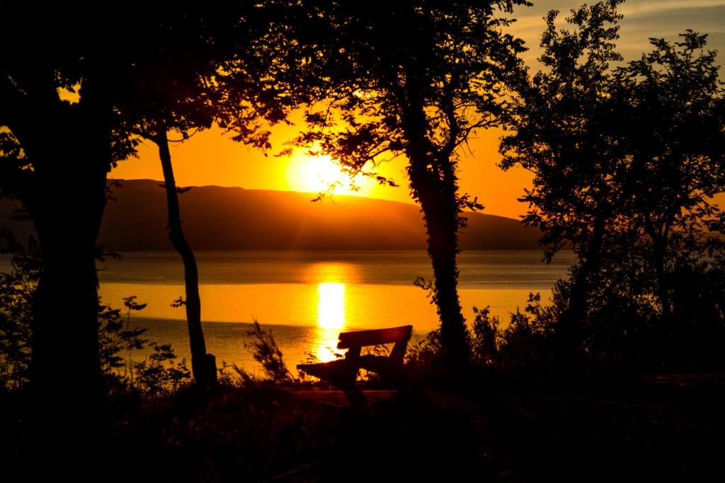 a bench sitting in front of a lake at sunset at Apartment Roby in Senj