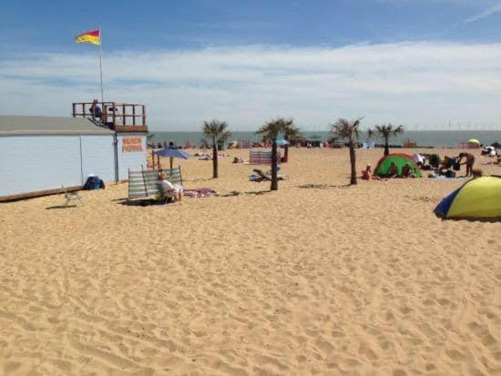 a beach with umbrellas and people on the sand at Clacton Caravan Hire in Little Clacton