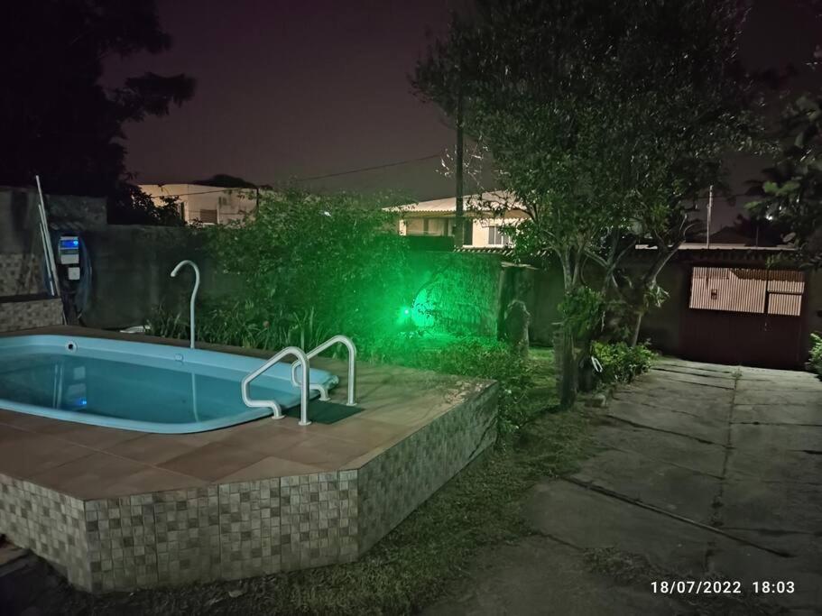 a jacuzzi tub in front of a house at night at Casa agradável com piscina a 200 metros da praia in Vila Velha