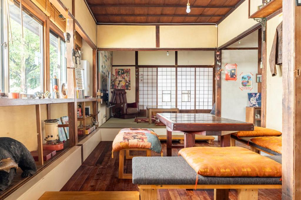 a room with a table and a bench in a room at 古民家一棟貸しの宿 Thank you Hippo Inn in Matsumoto